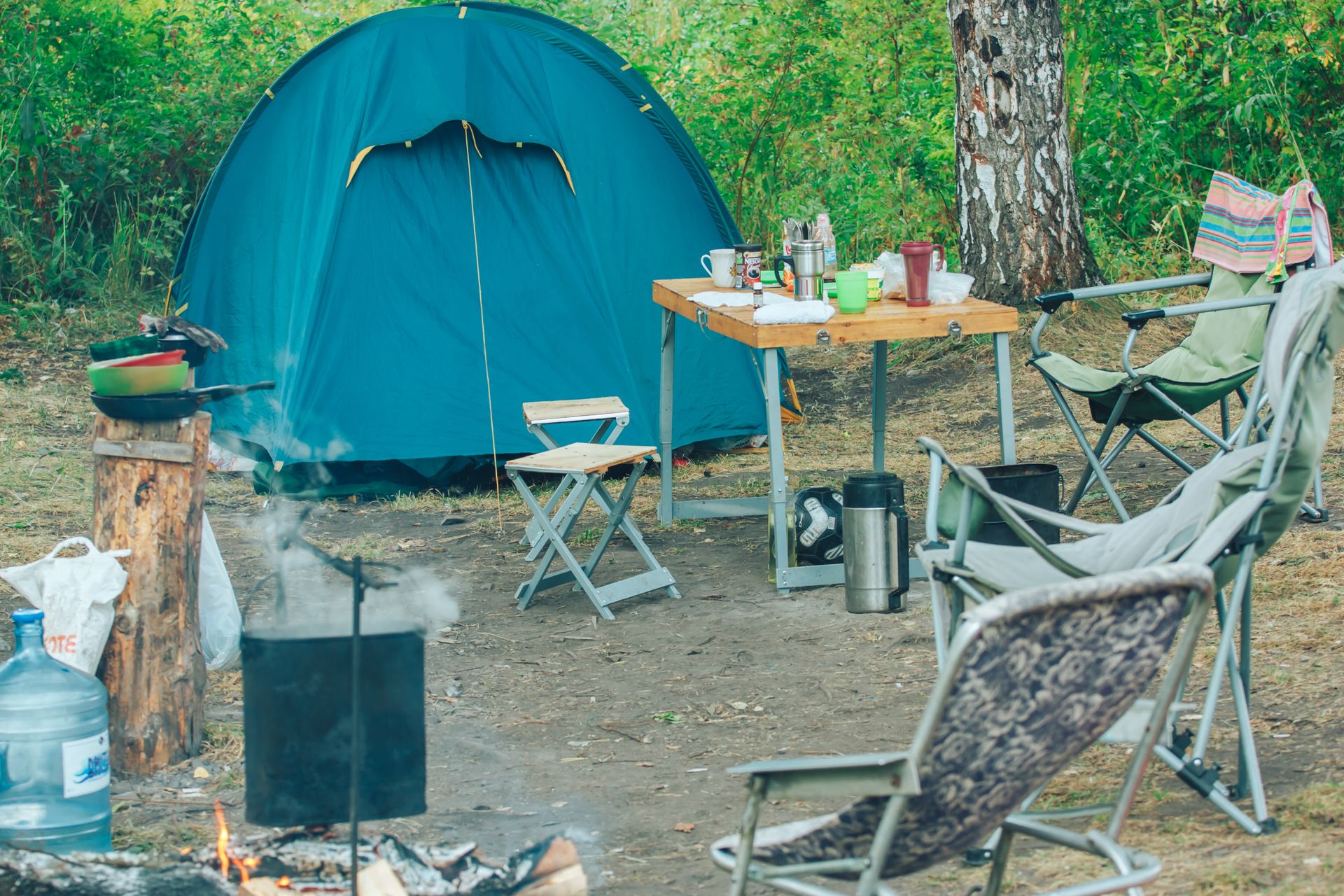 Kampeerplek met tent, campingtafel en kampvuur in het bos